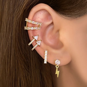 Close-up of five-piece gold ear jewelry set featuring CZ stud earrings and ear cuff