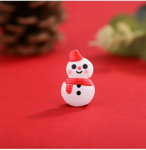 Close-up of a miniature resin snowman with red hat and scarf on a festive red background