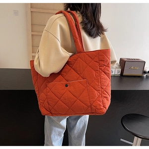 Detail of quilted rust orange tote bag with diamond stitching and front snap pocket