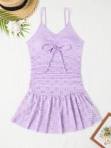 Flat lay of lavender eyelet swimsuit with ruffle hem and decorative beach accessories