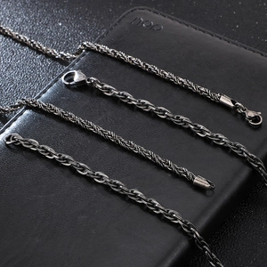 Detail view of various stainless steel punk chain necklaces on a black leather background