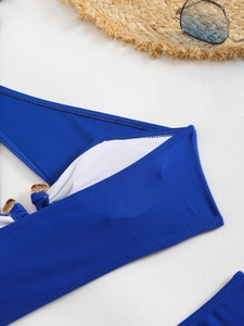 Close-up of royal blue bikini top featuring elegant gold metal rings and summer accessories