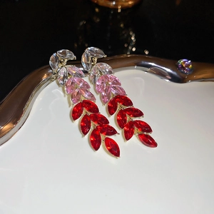Macro view of gradient leaf drop earrings with colorful crystals in gold claw settings