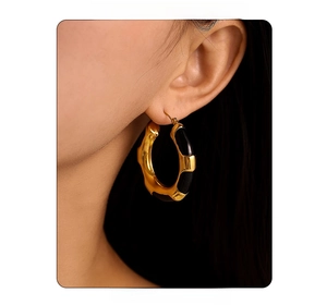 Close-up of model wearing gold-plated hoop earrings with black enamel leopard print