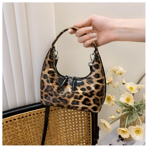Handheld view of a glossy leopard print crescent bag with black strap and silver hardware