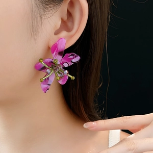 Close-up of vintage flower earrings with purple petals and green beads worn by a model