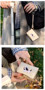 Detail of beige card wallet with cute dog embroidery and woven lanyard attachment