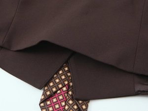 Close-up detail of brown woven vest fabric and patterned geometric necktie lining