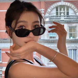 Retro black cat-eye sunglasses with oval frames and dark lenses shown on a female model