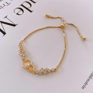 Detail of gold pull-bracelet with Wulu charm, cat-eye stone and white zircon stones