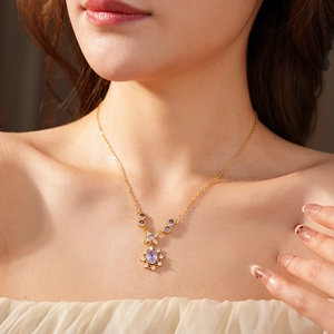 Detail of vintage gold necklace featuring a purple oval gemstone pendant and zircon accents