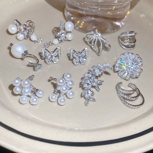 Detail of silver pearl and zircon earrings set arranged on a ceramic tray