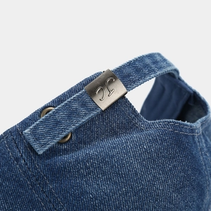 Macro detail of navy denim baseball cap featuring adjustable metal buckle with JC engraving