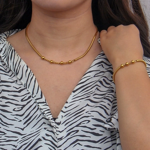 Detail of gold snake chain necklace and beaded bracelet set on zebra print background