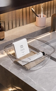 Detail of transparent square washbasin with hanging holes on marble countertop