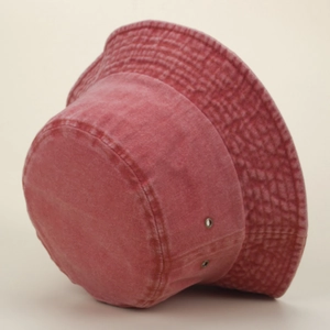 Détail d'un bob en jean délavé rouge avec œillets métalliques et coutures renforcées