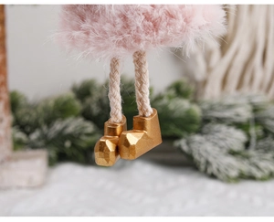 Close-up of pink plush Christmas ornament with braided legs and gold boots on tree