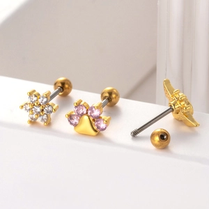 Detailed macro view of gold-tone flower, paw print, and wing stud earrings with screw backs