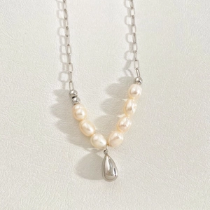 Detailed shot of stainless steel teardrop pendant and freshwater pearls on elegant chain