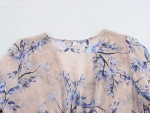 Détail du tissu en mousseline fleurie transparente et de l'encolure ronde de la robe