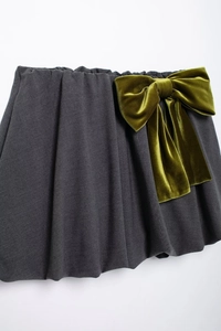 Détail de la mini-jupe plissée grise ornée d'un grand nœud en velours vert olive