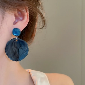 Detailed close-up of dark blue marble resin earrings worn to show wave texture and size