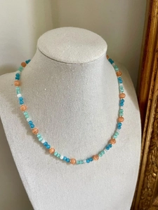 Detail of glacier blue cat eye beaded necklace with heart pendant on display