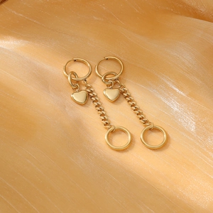 Golden stainless steel heart dangle earrings on elegant silk background texture