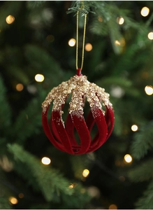 Detail of burgundy flocked Christmas ball with gold sequins and pearls on a lit tree