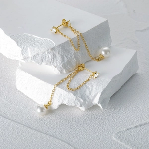 Detail view of S925 silver pearl tassel earrings on white stone background