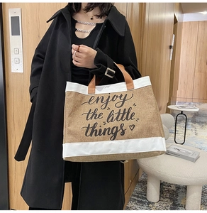 Detail of linen tote bag featuring 'enjoy the little things' print and leather handles