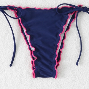 Detail of blue bikini bottoms with pink ruffle trim and side tie design on white texture