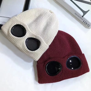 Detail showing thick knit beanies in cream and dark red with integrated goggles