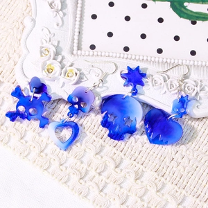 Blue skull and heart acrylic earrings set displayed on white textured fabric backdrop