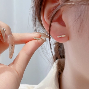 Detail of 925 silver gold stud earrings with cubic zirconia worn by a model