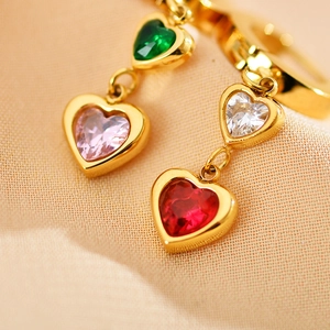 Orecchini d'oro con zirconi colorati a forma di cuore su morbido tessuto di seta rosa