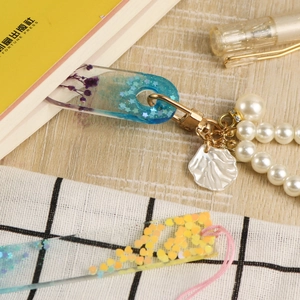 Detail of DIY heart bookmark mold with resin, dried flowers, and pearl pendant