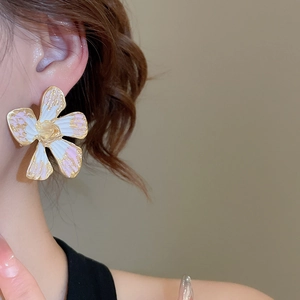 Close-up of elegant flower stud earring with pink and gold marble enamel on model