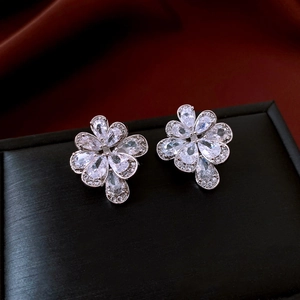 Macro shot of silver flower earrings with pear-shaped cubic zirconia on black leather