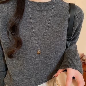 Detail of tiger eye stone pendant on a silver ball chain worn with a knit sweater