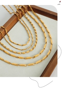 Close-up of gold two-tone bamboo link necklace with intricate Greek meander engravings