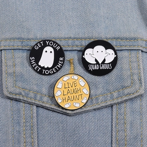 Three Halloween ghost enamel badges pinned on denim jacket with fun puns for stylish accessory