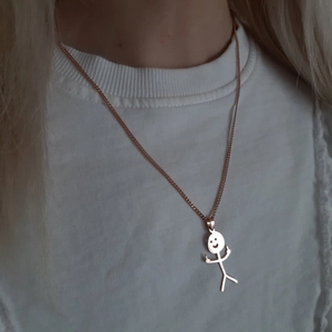 Detailed view of funny doodle necklace with middle finger stick figure pendant on model