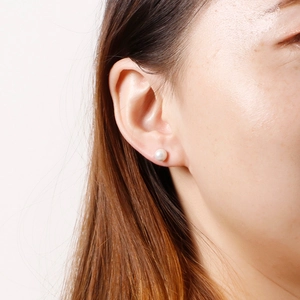 Close-up of minimalist white shell pearl stud earrings on model for an elegant look