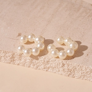 Detailed close-up of C-shaped pearl ear cuffs with a minimalist metallic finish for women