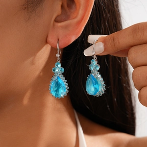 Close-up of elegant light blue pear-shaped zircon earrings with floral silver accents
