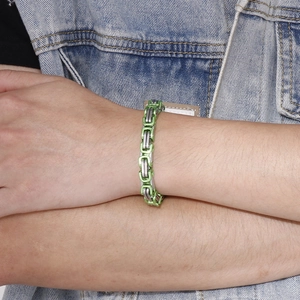 Close-up of green and silver stainless steel king chain bracelet worn with denim jacket