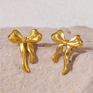 Élégantes boucles d'oreilles nœud dorées avec finition polie sur fond de pierre naturelle