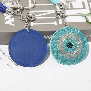 Detailed view of evil eye keychains with rhinestones, tassels, and silver bells on background