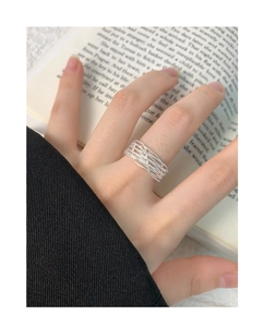 Detailed shot of multi-layer woven silver ring on finger with artistic book background